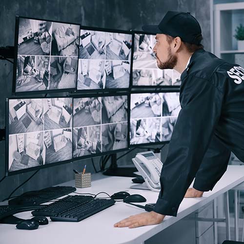 Agent de vidéosurveillance devant un mur d'écrans