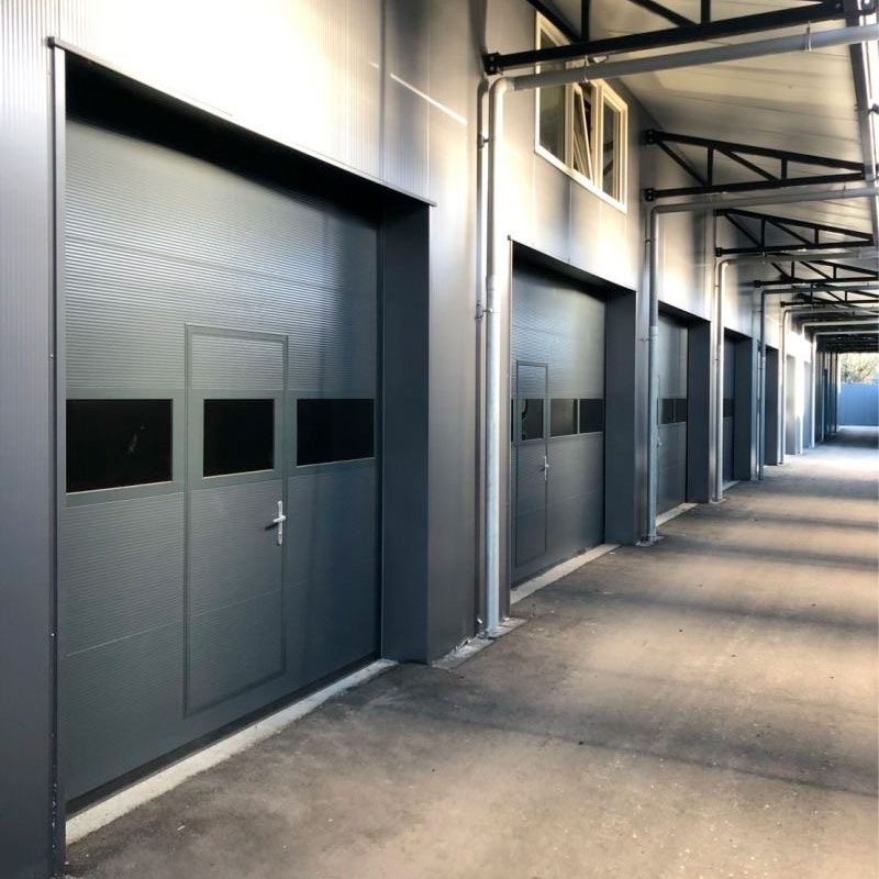 Portalp porte sectionnelle Alpha Deuren ISO, isolée pleine avec hublots et portillon piéton
