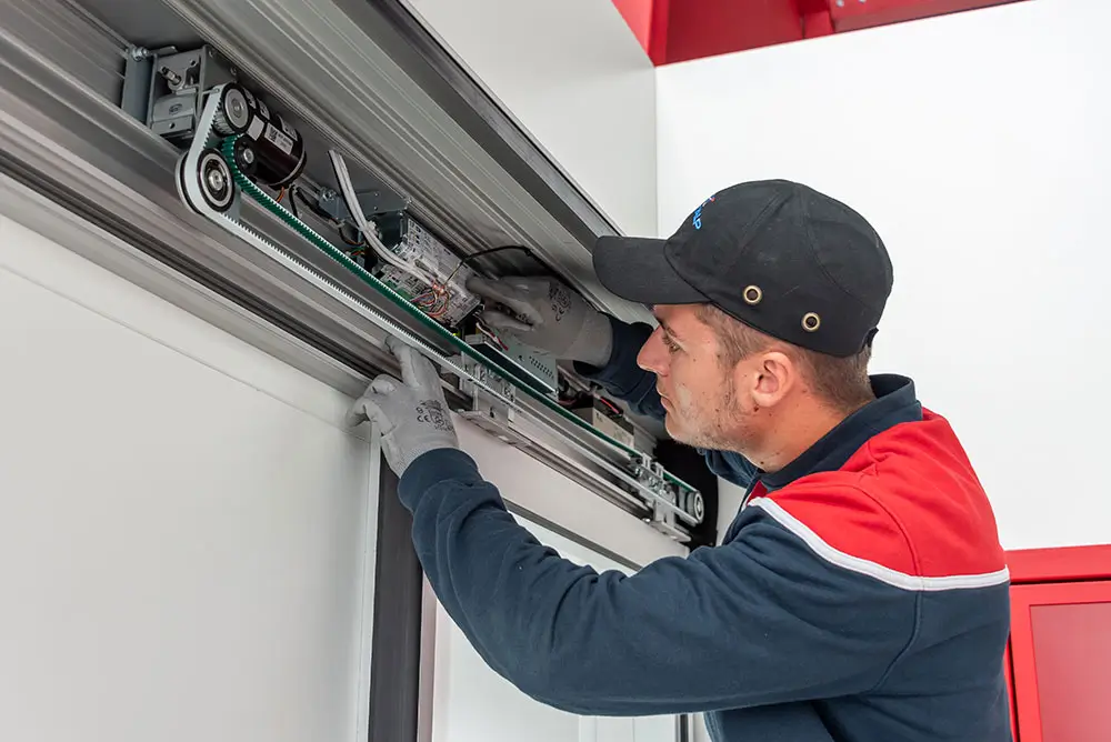Technicien réalisant la maintenance d'une porte automatique